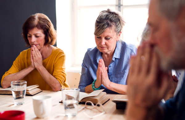 Senior people in bible reading group in community center club, praying.