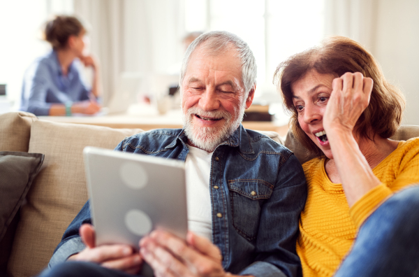 Senior couple using tablet in community center club, technology in everyday life concept.