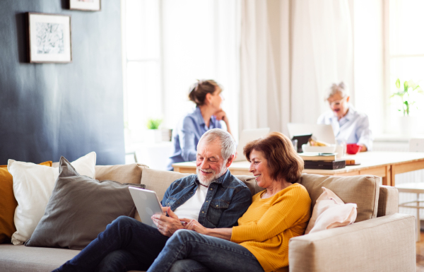 Senior couple using tablet in community center club, technology in everyday life concept.