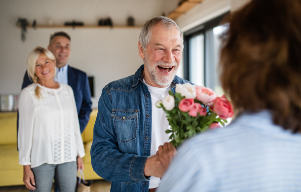 A group of cheerful senior friends at dinner party at home, greeting.