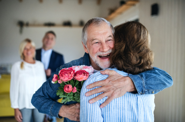 A group of cheerful senior friends at dinner party at home, greeting.