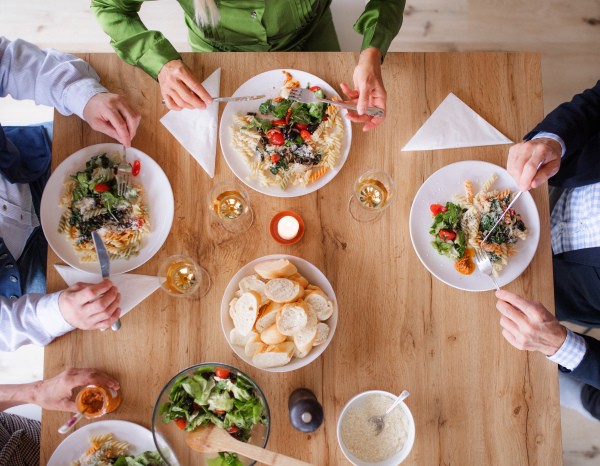 Top view of group of senior friends at dinner party at home, eating. A midsection.