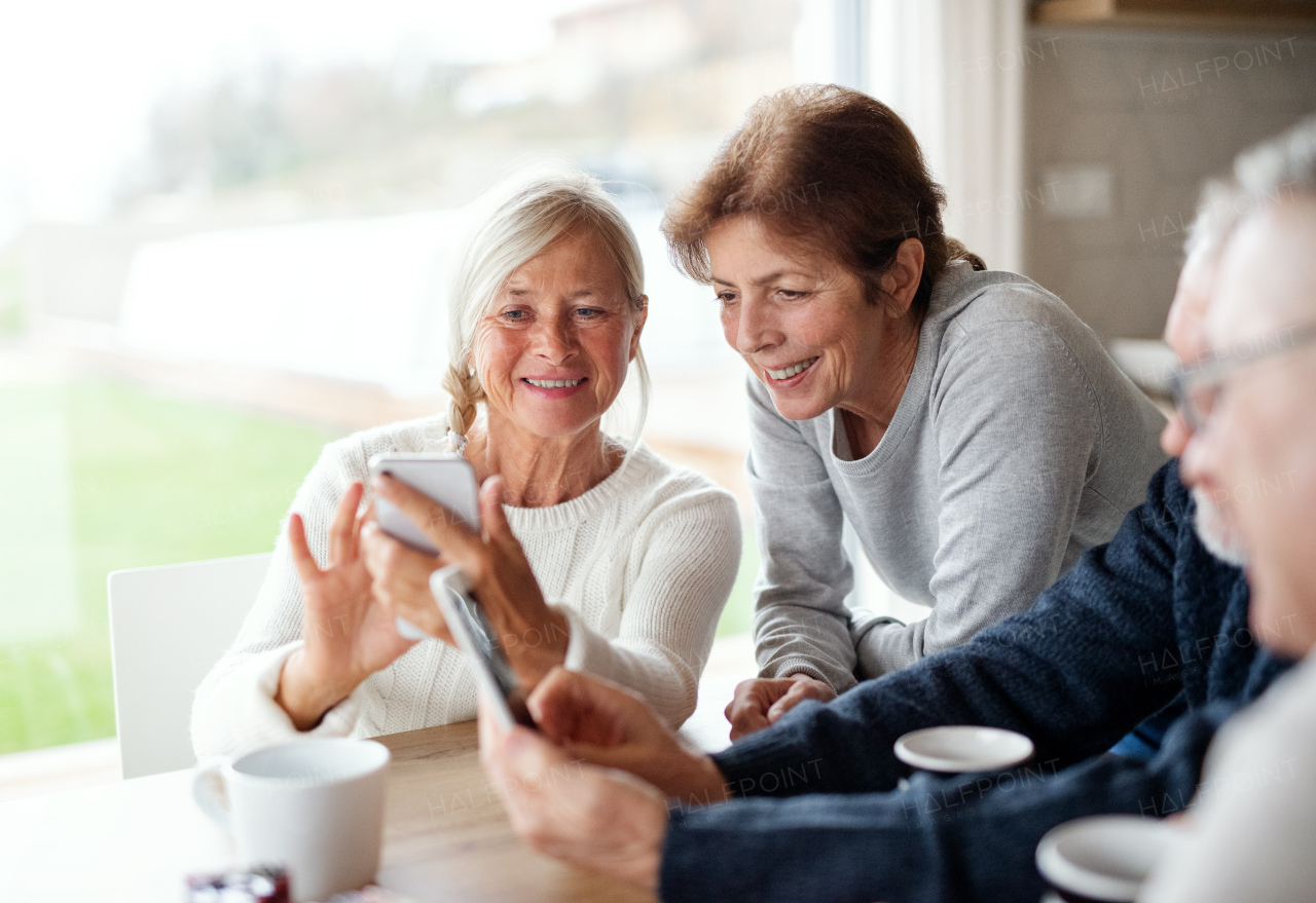 A group of senior friends at home, using smartphones.