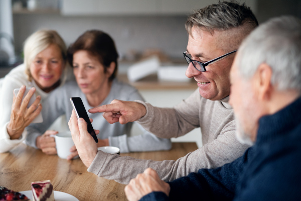 A group of senior friends at home, using smartphones.