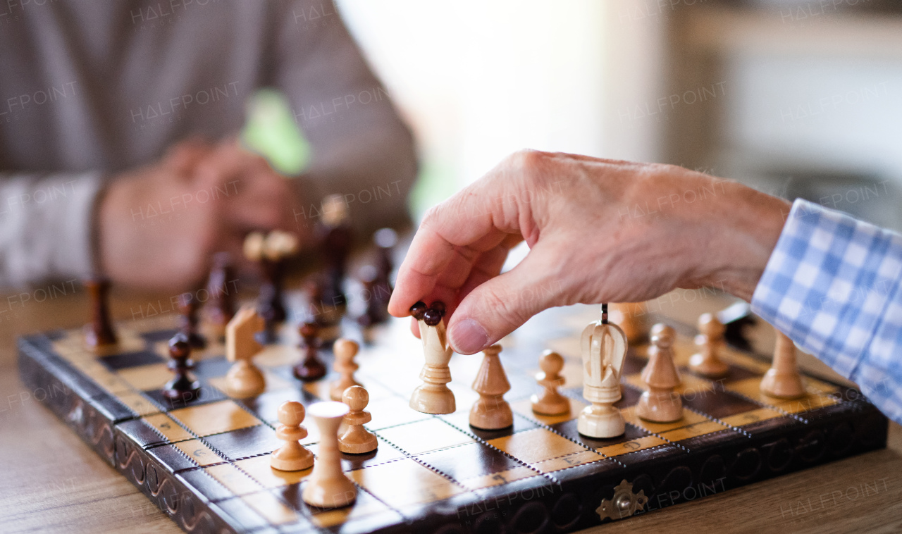 Midsection of unrecognizable senior men friends at home, playing chess.