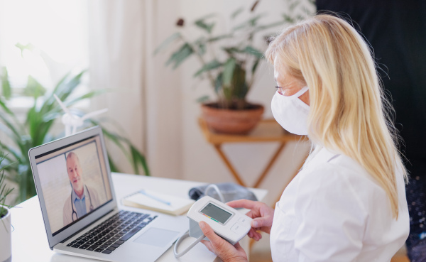 Senior woman with laptop indoors at home , consulting doctor and video call concept.