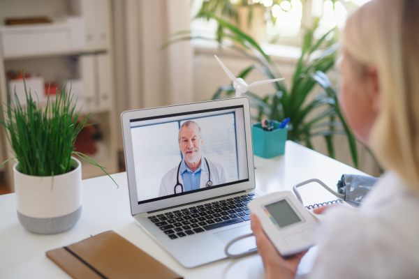 Senior woman with laptop indoors at home, consulting doctor and video call concept.