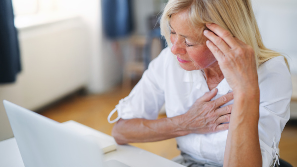 Frustrated and tired woman engineer with laptop indoors in home office, feeling pain.