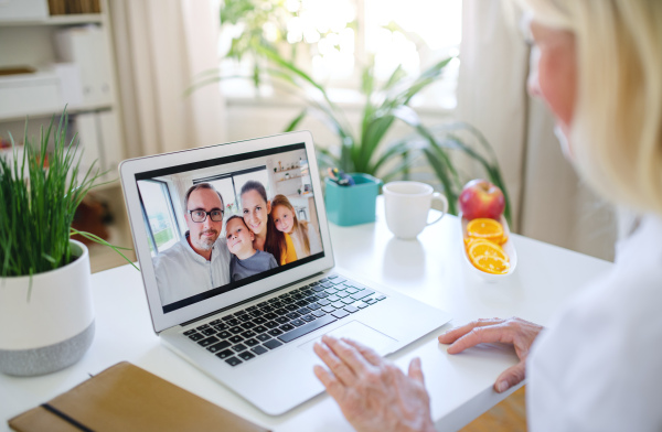 Happy senior woman with laptop indoors at home, family video call concept.