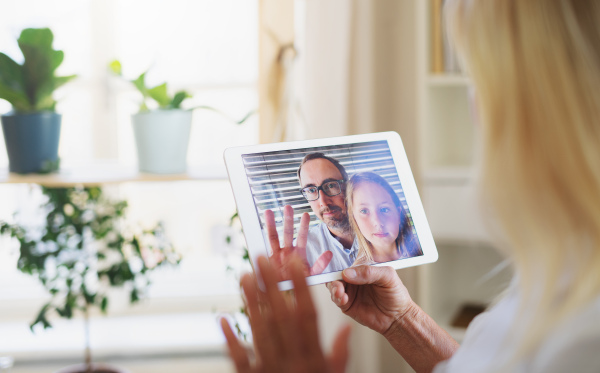 Happy senior woman with laptop indoors at home, family video call concept.