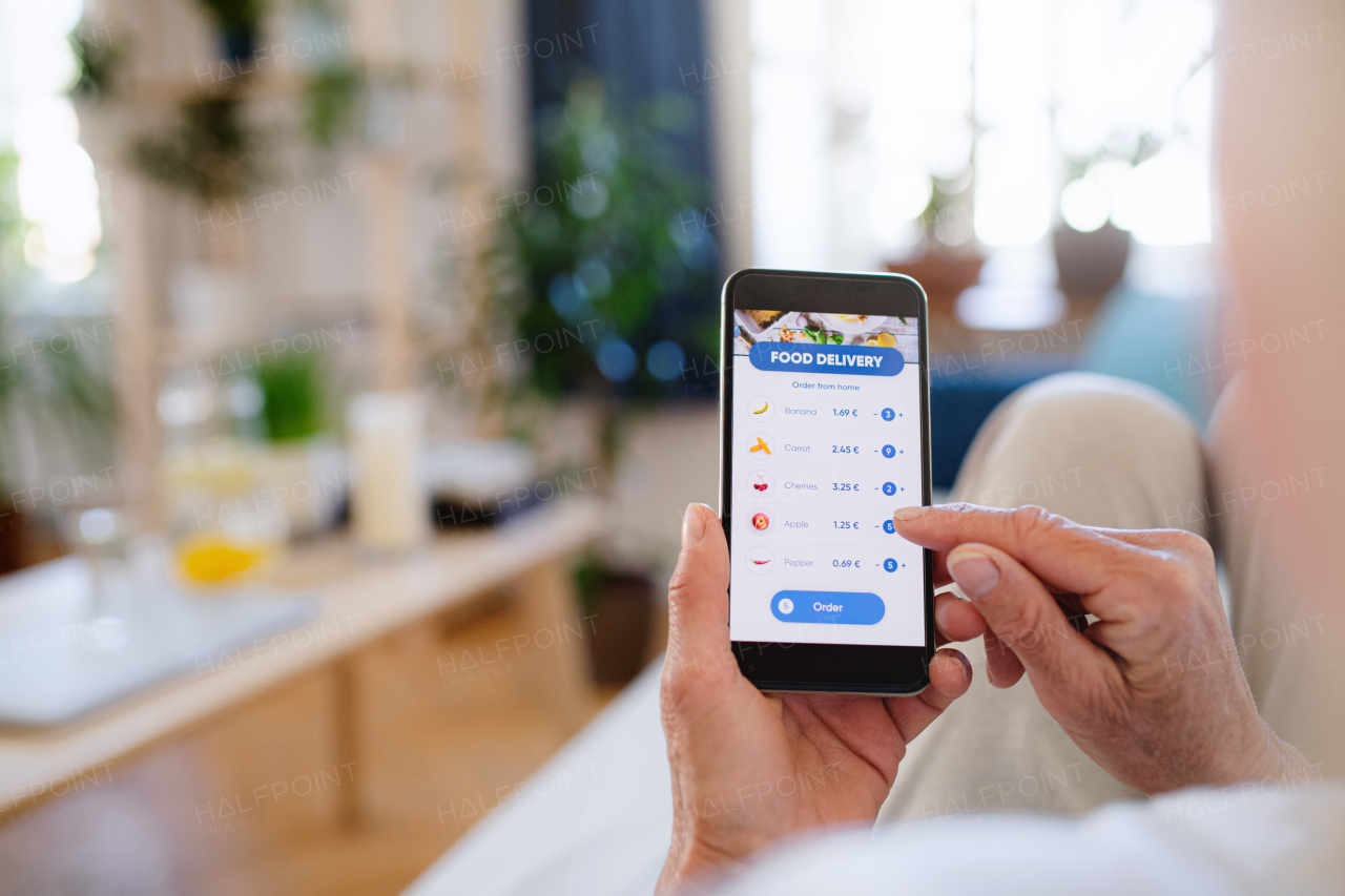 Unrecognizable woman with smartphone indoors at home, ordering food online.