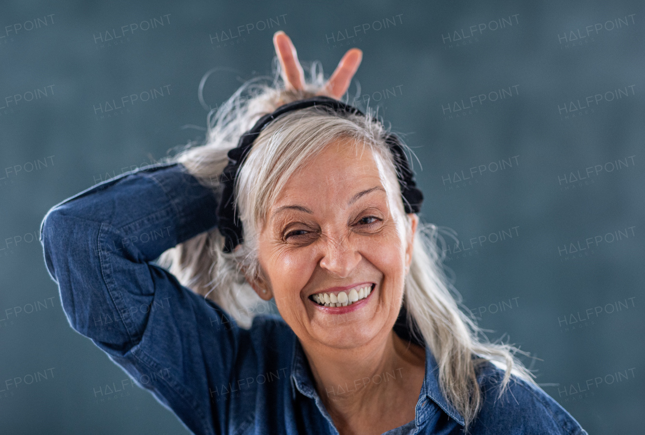 Front view portrait of senior woman standing indoors against dark background, looking at camera.