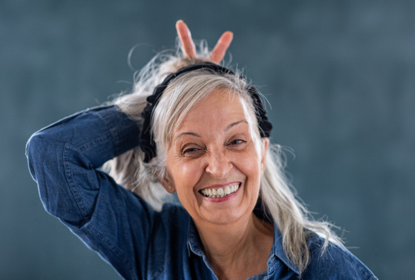 Front view portrait of senior woman standing indoors against dark background, looking at camera.