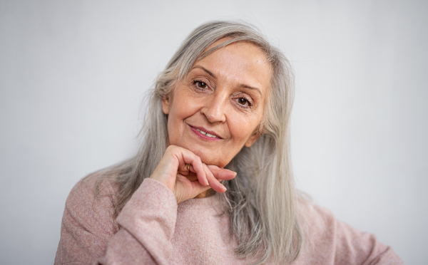 Front view portrait of happy senior woman standing indoors at home, looking at camera.