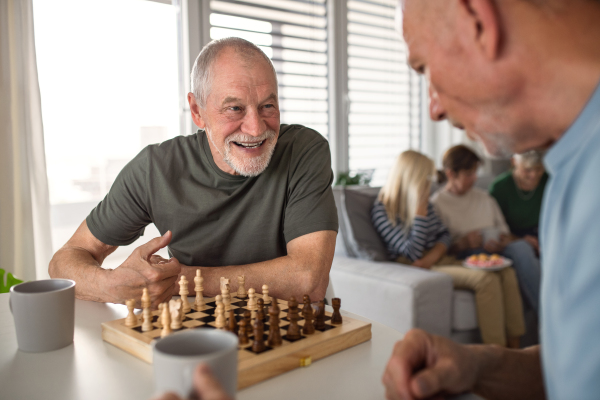 Group of happy senior friends playing board games indoors, party and social gathering concept.