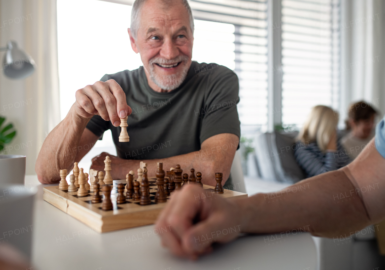 Group of happy senior friends playing board games indoors, party and social gathering concept.