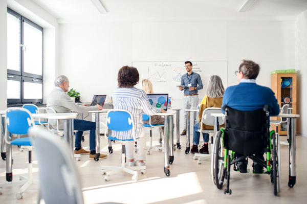 Group of cheerful senior people attending computer and technology education class.