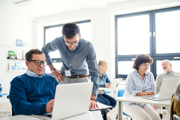 Group of cheerful senior people attending computer and technology education class.