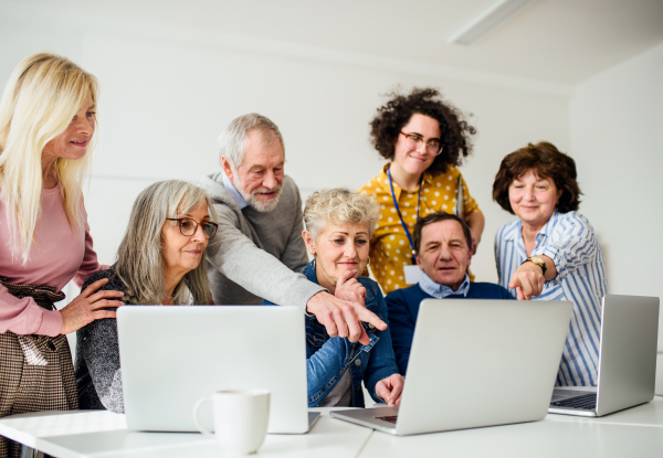 Group of cheerful senior people attending computer and technology education class.