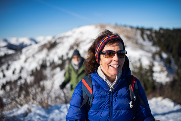 Portrait of senior woman with husband hiking in snow-covered winter nature.