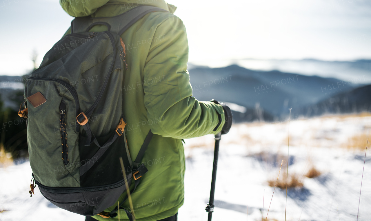 Midsection of unrecognizable man standing in snow-covered winter nature. Copy space.