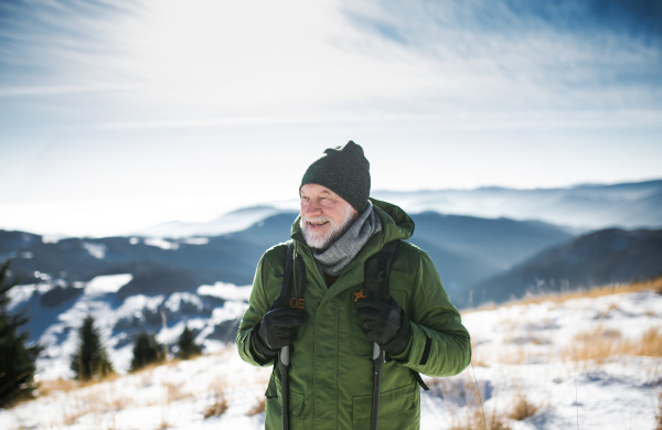 Front view portrait of senior man standing in snow-covered winter nature.