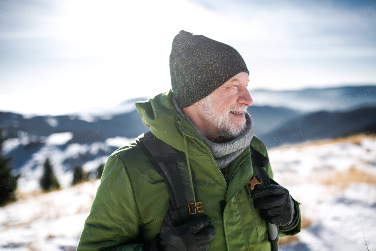 Front view portrait of senior man standing in snow-covered winter nature.