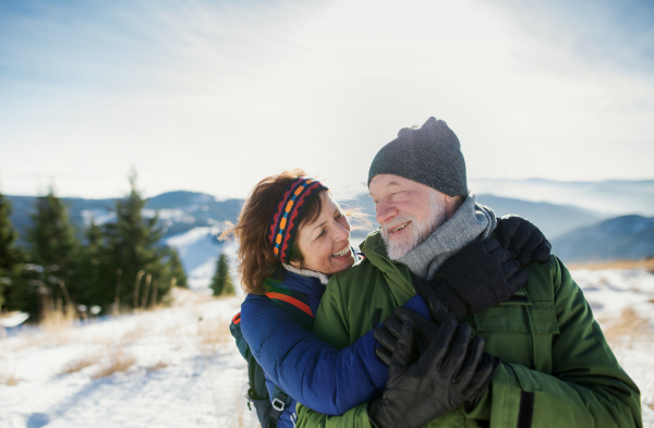 Front view portrait of senior couple hikers standing in snow-covered winter nature.