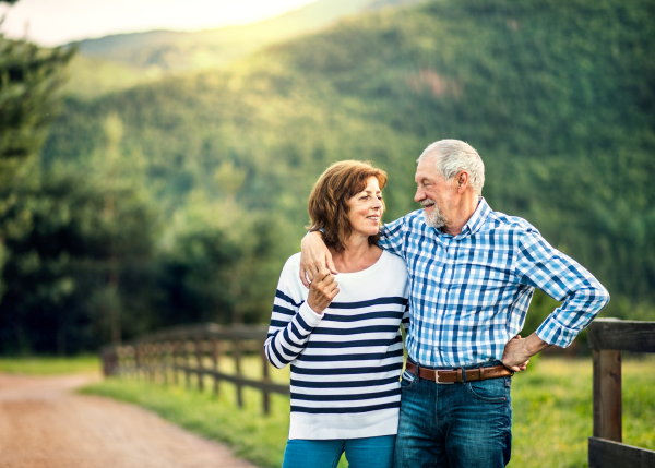 A joyful senior couple in love looking at each other outside in nature. Copy space.