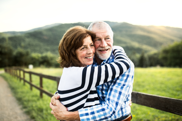 A close-up of a joyful senior couple hugging outside in nature.