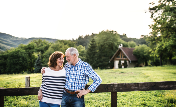 A joyful senior couple in love looking at each other outside in nature. Copy space.