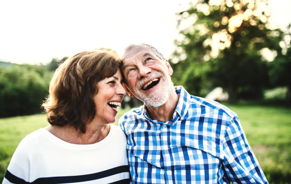 A joyful senior couple in love outdoors in nature, laughing.