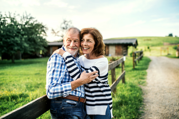 A senior couple in love standing outdoors in nature, hugging. Copy space.