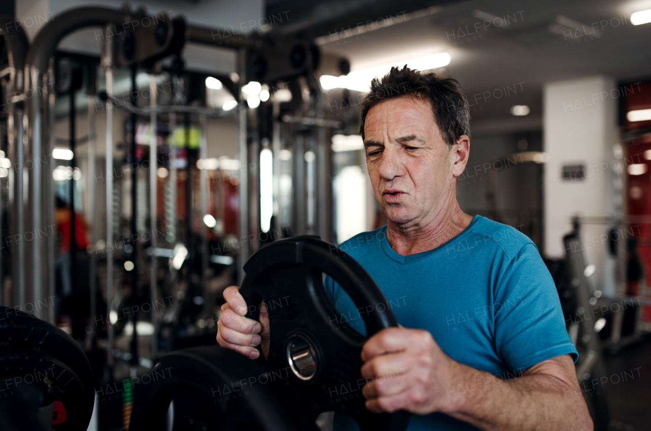 A senior man doing strength workout exercise in gym. A copy space.