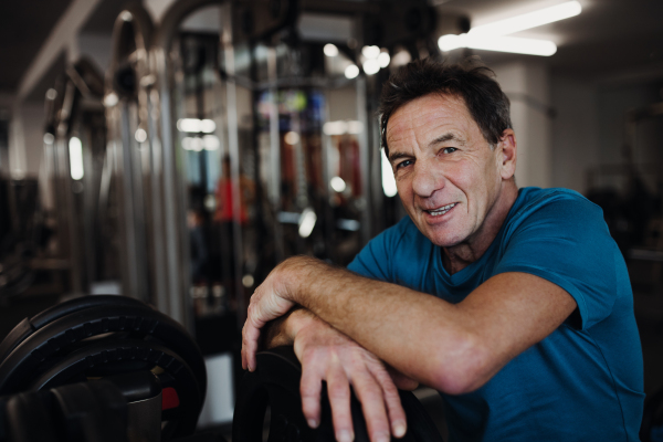 A happy senior man resting after workout exercise in gym. Copy space.