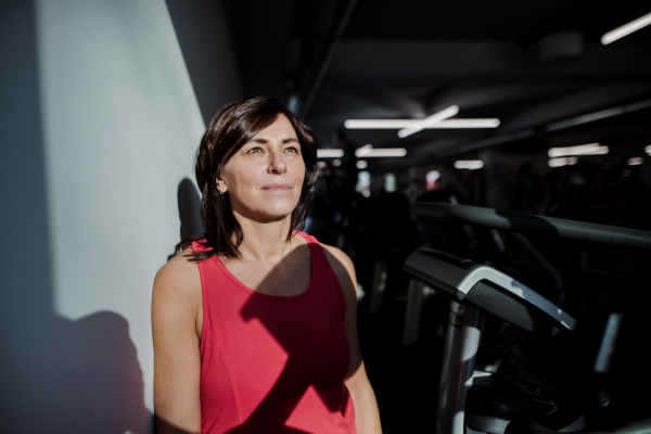 A content senior woman in gym resting after doing exercise. Copy space.