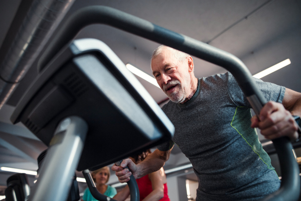 A senior man doing strength workout exercise in gym. A copy space.