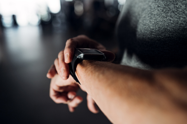 A midsection of man with smartwatch in gym measuring time while doing exercise. Copy space.