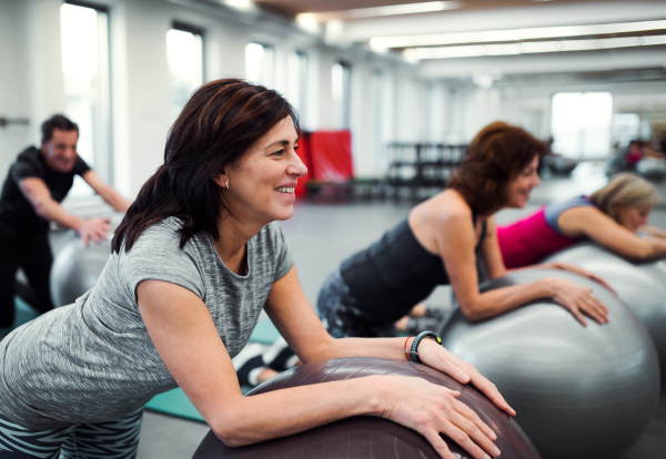 A group of cheerful female seniors in gym doing exercise on fit balls.