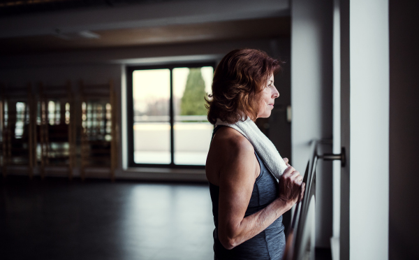 A content senior woman in gym resting after doing exercise. Copy space.