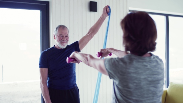 A happy senior couple indoors at home, doing exercise indoors.