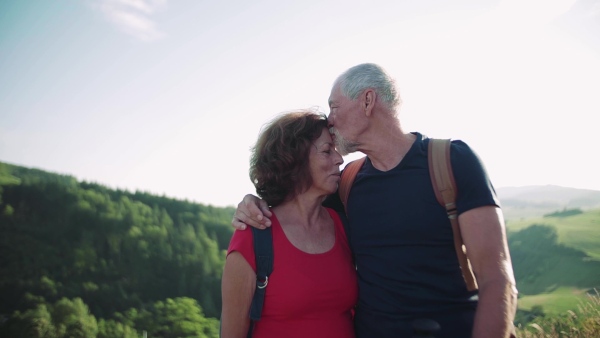 Senior tourist couple travellers hiking in nature, kissing when resting. Slow motion.