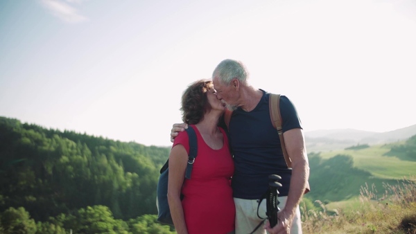 Senior tourist couple travellers hiking in nature, kissing when resting. Slow motion.