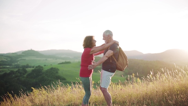 Senior tourist couple travellers hiking in nature, hugging when resting. Slow motion.