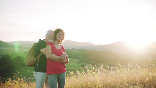 Senior tourist couple travellers hiking in nature, hugging when resting. Slow motion.