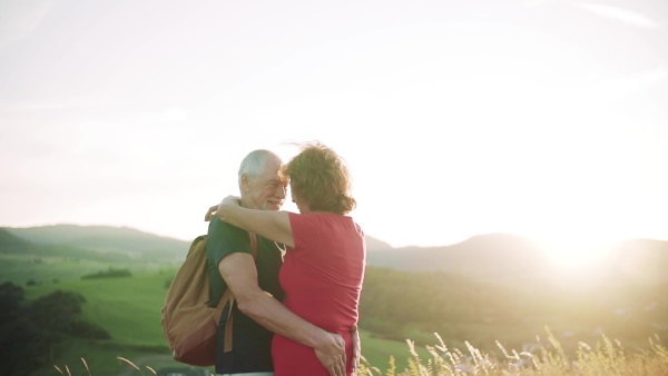 Senior tourist couple travellers hiking in nature, hugging when resting. Slow motion.