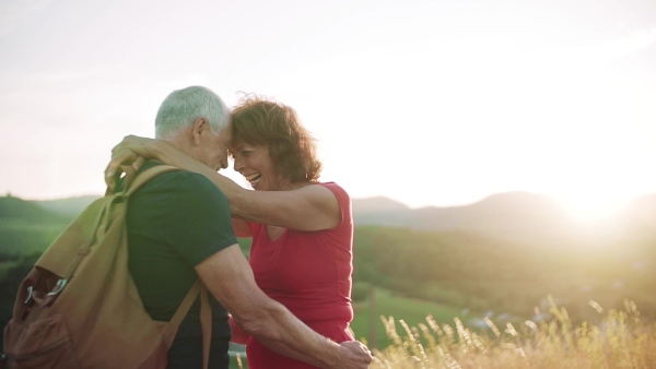 Senior tourist couple travellers hiking in nature, hugging when resting. Slow motion.