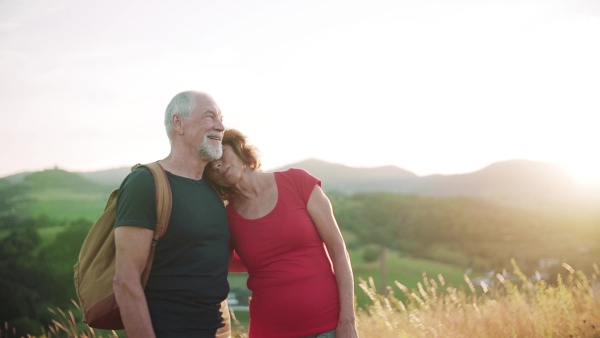 Senior tourist couple travellers hiking in nature, hugging when resting. Slow motion.