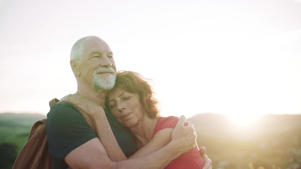 Senior tourist couple travellers hiking in nature, hugging when resting. Slow motion.