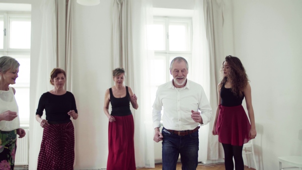 A group of senior people attending dancing class with dance teacher.